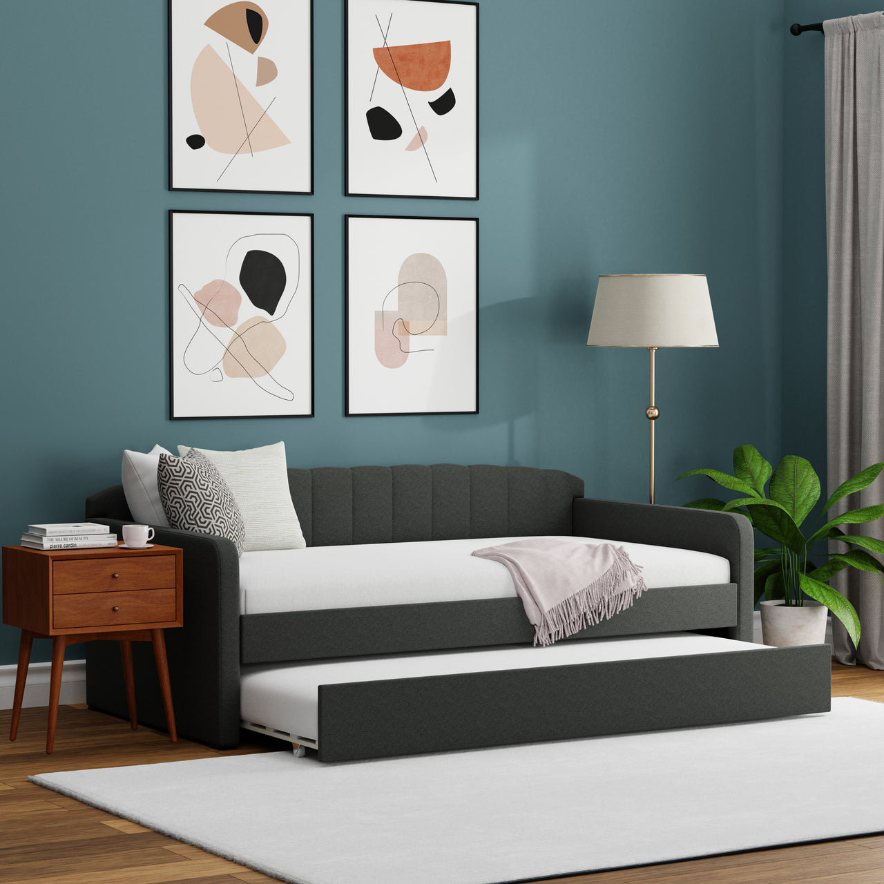 Modern living room with a gray sofa bed, wooden side table, and abstract wall art.