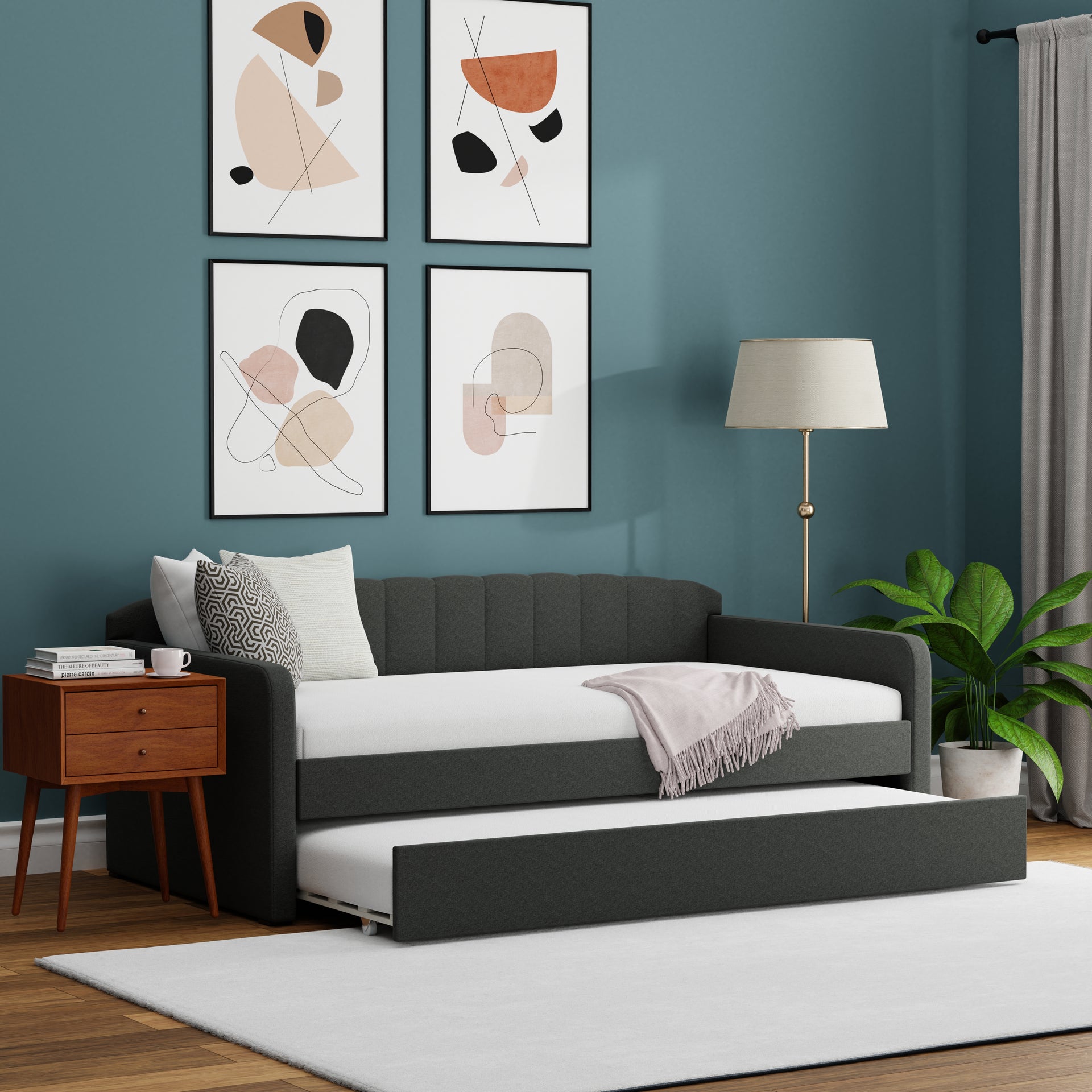 Modern living room with a gray sofa bed, wooden side table, and abstract wall art.