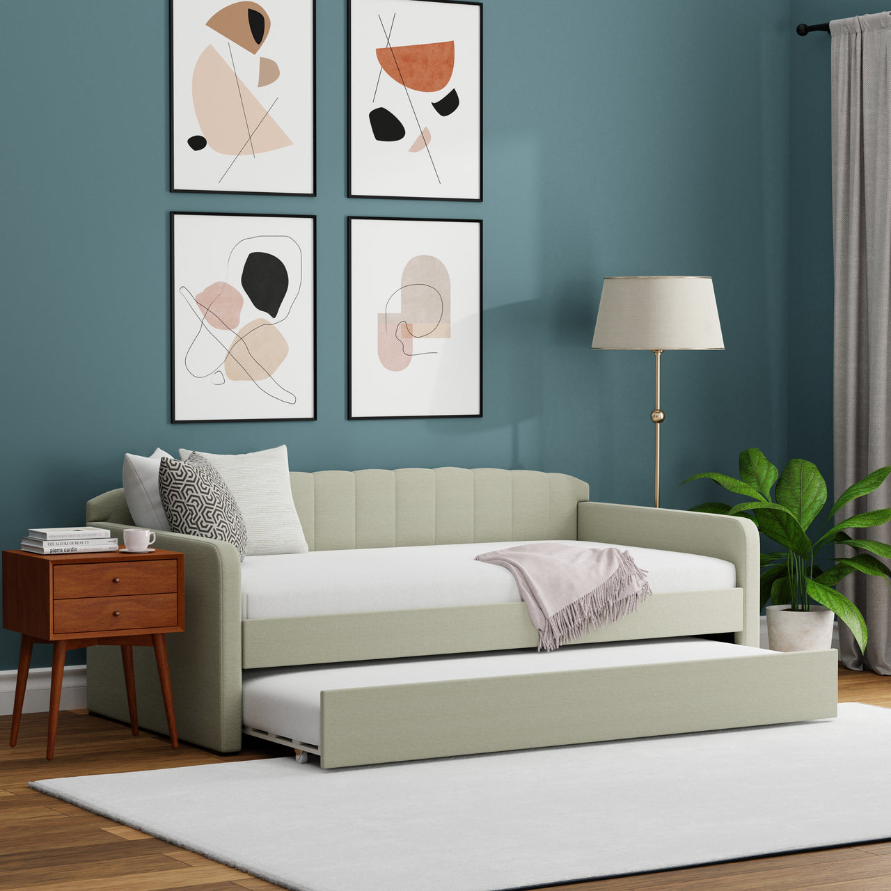 Light sofa bed in a room with abstract art on the wall, a lamp, and a plant.