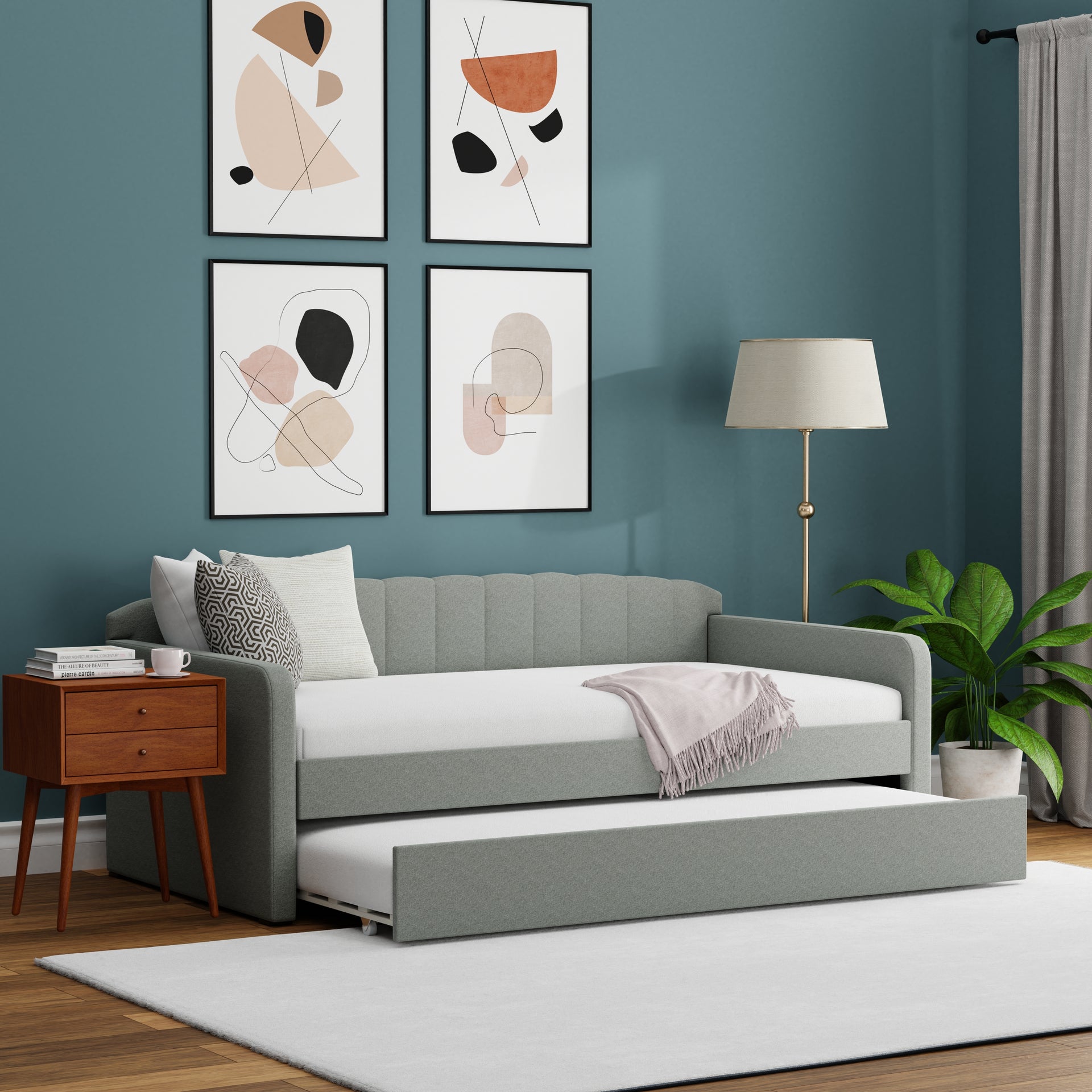 Gray sofa bed in a room with abstract art on the wall and a lamp.