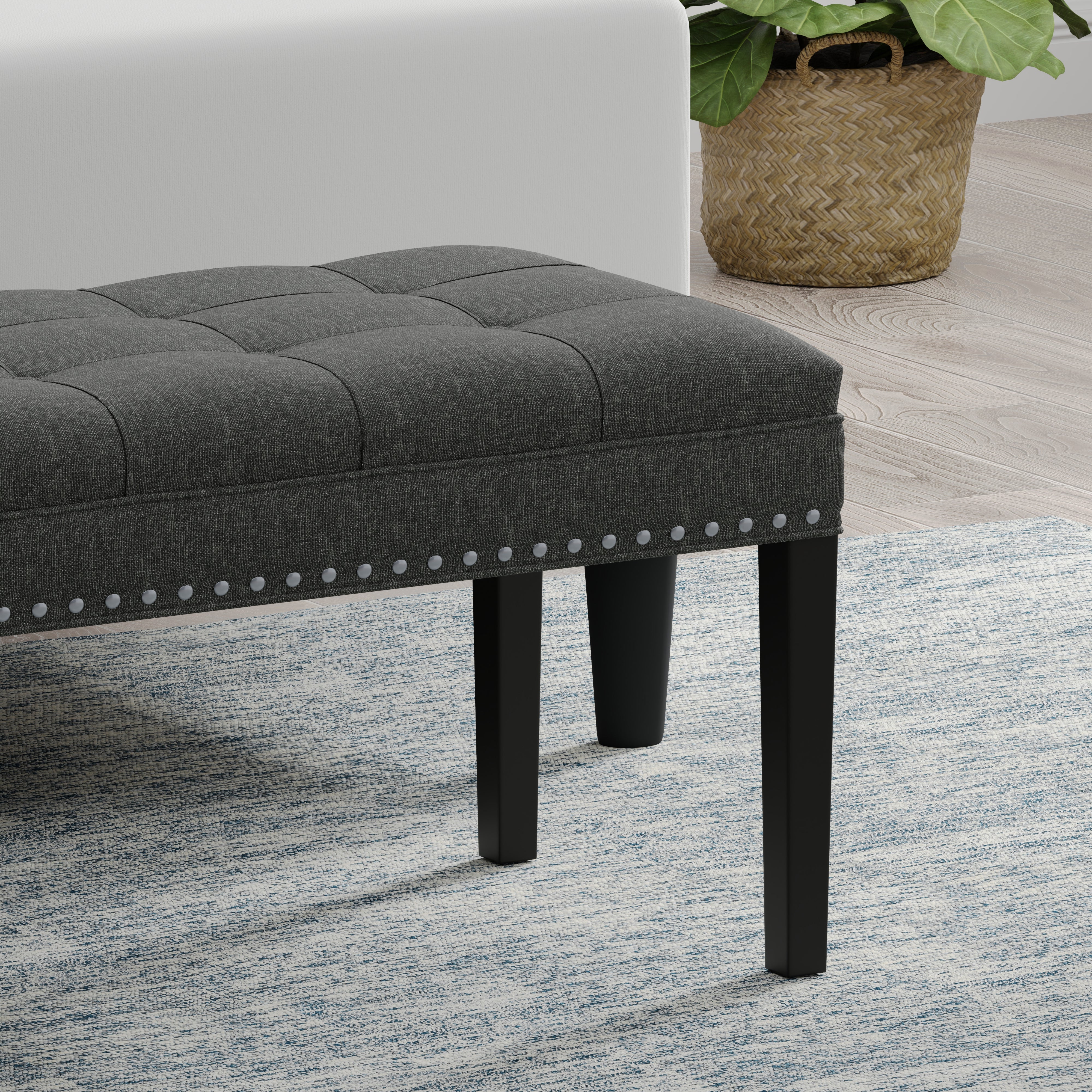 Gray upholstered bench with black legs on a patterned rug