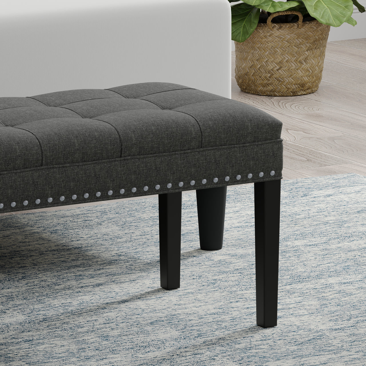 Gray upholstered bench with black legs on a patterned rug