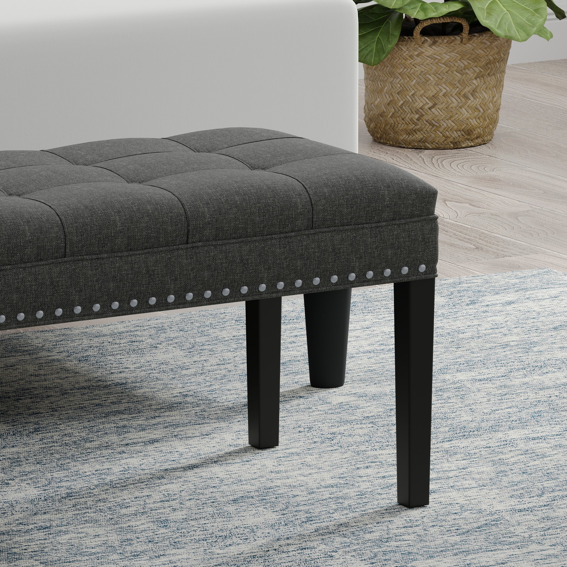 Gray upholstered bench with black legs on a patterned rug